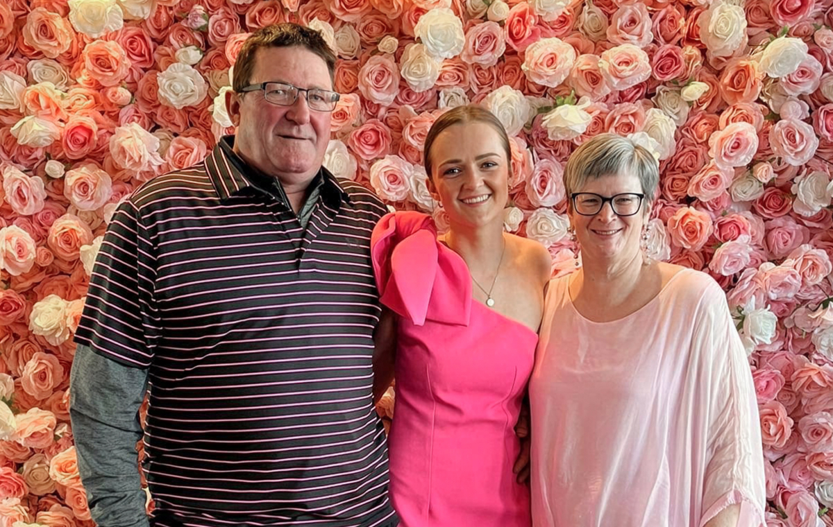 Sophie Jordon with parents, standing in front of a rose wall backdrop